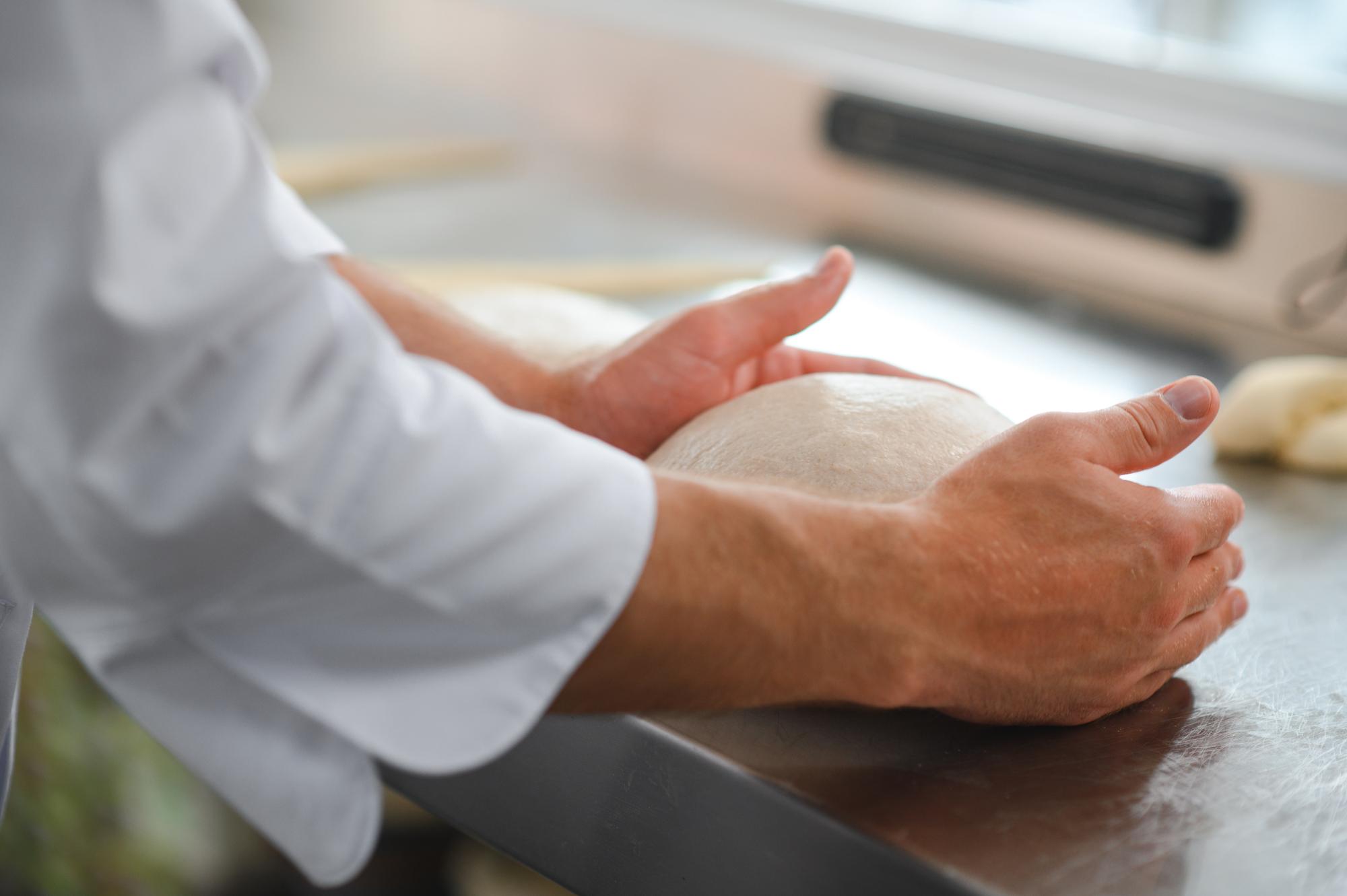 Dettaglio di mani che impastano pane artigianale